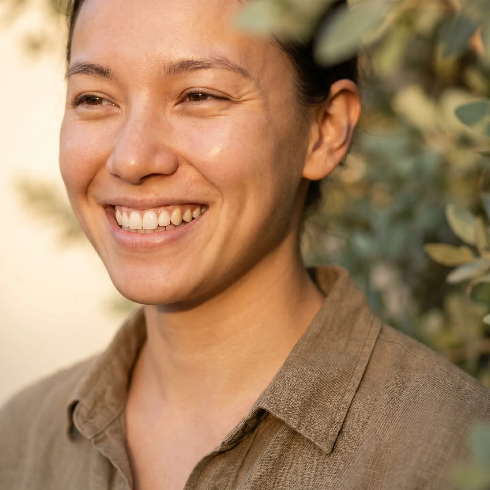 A close-up of a woman laughing outdoors.